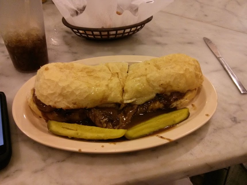 This is a po' boy. This particular po' boy has thick-sliced roast beef, swiss cheese, grilled onions, and gravy, of all things.